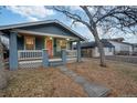 Charming blue home with a welcoming front porch and a delightful pink front door at 1560 Clinton St, Aurora, CO 80010