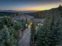 Beautiful aerial view of estate home nestled within the trees with mountain views at sunset at 28154 Belle Mont Trl, Conifer, CO 80433