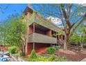 Exterior side view of building with balcony, stairs and landscaped yard with beautiful mature tree at 3050 W 32Nd Ave # 104C, Denver, CO 80211