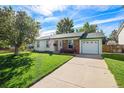 Ranch style home with a green trimmed roof, attached garage, and a nicely landscaped lawn at 16598 E Lasalle Pl, Aurora, CO 80013