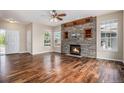 Open living room showcasing hardwood floors, a stone fireplace, and large windows at 3389 Willowrun Dr, Castle Rock, CO 80109