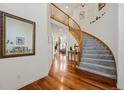 Elegant foyer with hardwood floors, a curved staircase, and a decorative mirror, creating a welcoming entrance at 10908 Eagle Run Dr, Parker, CO 80138