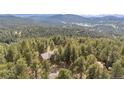 Stunning aerial view of the home nestled among towering pine trees with mountain views at 4992 White House Trl, Evergreen, CO 80439