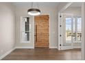 Bright foyer featuring a modern light fixture, sleek hardwood floors, and an impressive stained wood front door at 8014 Trinity Peak Ln, Castle Rock, CO 80108