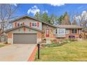 Quaint two-story home with gray siding, a red front door, an attached garage, and landscaped front yard at 7148 S Dahlia Ct, Centennial, CO 80122