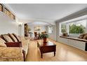 Inviting living room with hardwood floors, comfortable seating, a bay window, and views of the dining room at 7148 S Dahlia Ct, Centennial, CO 80122