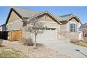 View of the home featuring a two-car garage, stone accents, and low maintenance yard at 24437 E Powers Ave, Aurora, CO 80016
