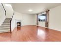 Inviting living room with hardwood floors, a cozy fireplace, and a staircase leading to the upper level at 3310 Quicksilver Rd, Frederick, CO 80516