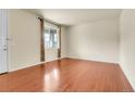 Bright living room features hardwood floors, a large window with curtains, and neutral wall paint at 3310 Quicksilver Rd, Frederick, CO 80516