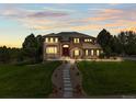 The front exterior of the home is well lit during twilight showcasing the stone accents and manicured front lawn at 8518 High Ridge, Castle Pines, CO 80108