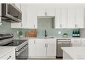 Beautiful, white kitchen with modern stainless steel appliances, herringbone backsplash, and white countertops at 6539 Pinewood Dr # 57, Parker, CO 80134