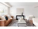 Bright living room featuring a leather sofa, two white armchairs, and modern decor at 2756 E Euclid Ave, Centennial, CO 80121