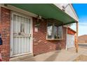 Front door entrance with security gate and brick facade at 5493 Quari St, Denver, CO 80239