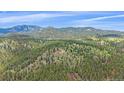 Beautiful aerial view of the home surrounded by lush greenery, mountains, and blue skies at 31231 Red Hawk Trl, Conifer, CO 80433