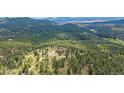 Expansive aerial shot of the home on acreage surrounded by lush forestry and mountainous views at 31231 Red Hawk Trl, Conifer, CO 80433
