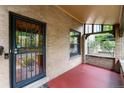 Inviting covered front porch with brick walls, red flooring, and decorative security door at 1308 York St, Denver, CO 80206