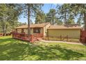 Exterior of a cozy home with a wooden deck, surrounded by lush greenery and mature trees at 30400 Hilltop Dr, Evergreen, CO 80439