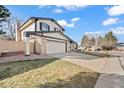 View of a two-story home with an attached garage and long driveway at 8405 W 74Th Dr, Arvada, CO 80005