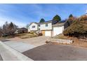 Split-level home featuring gray siding, brick accents, an attached garage, and solar panels against a clear blue sky at 717 Anderson St, Castle Rock, CO 80104