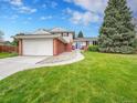 Well-maintained two-story home with manicured front lawn, concrete driveway, and brick accents at 1860 E Geddes S Cir, Centennial, CO 80122