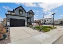 Modern two-story home with a spacious driveway, gray siding, black trim and a well-manicured lawn at 6454 Leathers Ln, Parker, CO 80134