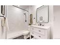 Bathroom with a modern vanity, sleek black hardware, white marble walls, and walk in shower at 7932 E 49Th Pl, Denver, CO 80238