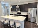Modern kitchen with stainless steel appliances, dark cabinets, a center island, and stylish pendant lighting at 7932 E 49Th Pl, Denver, CO 80238