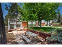 Backyard featuring a stone patio with picnic table, mature trees, and landscaping at 33589 Robin Ct, Elizabeth, CO 80107