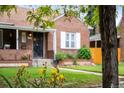 Brick home with tidy lawn and flowerbeds in the foreground, partially obscured by tree, creating a warm and inviting vibe at 1429 Hudson St, Denver, CO 80220