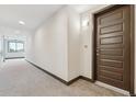 Carpeted hallway leading to unit entrance with brown front door at 485 Interlocken Blvd # 201, Broomfield, CO 80021
