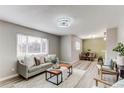 Bright living room showcases modern design, gray sofa, wood floors, and open flow to dining space at 9141 Gail Ct, Thornton, CO 80229