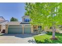 Charming two-story home featuring a three car garage, brick accents, a covered porch, and professionally landscaped front yard at 15432 Greenstone Cir, Parker, CO 80134