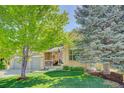 Inviting home with a covered porch, American flag, and mature trees on a well-manicured lawn at 15432 Greenstone Cir, Parker, CO 80134