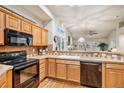 Kitchen with wood cabinets, black appliances, and tile countertops at 3275 S Indiana St, Lakewood, CO 80228