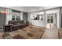 An open-concept living room with hardwood floors, gray walls, and a view of the modern kitchen at 747 Mockingbird St, Brighton, CO 80601