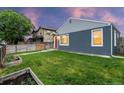 Lovely single-story house with blue siding and a vibrant red front door, nestled in a green yard with garden beds at 1414 W Nevada Pl, Denver, CO 80223