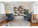 Bright living room featuring a decorative rug, two comfortable chairs, floating shelves, and hardwood floors at 10535 Laurelglen Cir, Highlands Ranch, CO 80130