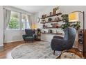 Cozy living room featuring hardwood floors, two chairs, decor shelves, and natural light from the nearby windows at 10535 Laurelglen Cir, Highlands Ranch, CO 80130