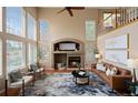 Bright living room with soaring ceilings, a cozy fireplace, and ample natural light from large windows at 9743 Las Colinas Dr, Lone Tree, CO 80124