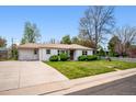 Inviting single-story home featuring a well-manicured lawn, mature trees, and an extended driveway leading to a one car garage at 8020 W 46Th Cir, Wheat Ridge, CO 80033