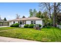 Well-maintained single-Gathering home with green lawn, mature trees, and landscaped front yard. Lawn has lush green grass at 8020 W 46Th Cir, Wheat Ridge, CO 80033