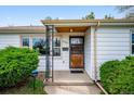 Close-up of a front porch with metal security door, framed window and manicured bushes at 8020 W 46Th Cir, Wheat Ridge, CO 80033