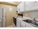 Galley style kitchen with white cabinets, range, microwave and tile flooring at 625 N Pennsylvania St # 208, Denver, CO 80203