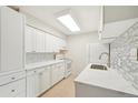 Updated kitchen with stainless steel sink, white cabinets, and backsplash at 7395 E Quincy Ave # 207, Denver, CO 80237