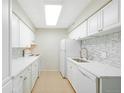 Bright kitchen featuring all white cabinetry, appliances, countertops, and a mosaic tile backsplash at 7395 E Quincy Ave # 207, Denver, CO 80237