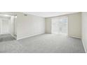 Open living room area with plush gray carpeting and a sliding glass door at 7395 E Quincy Ave # 207, Denver, CO 80237