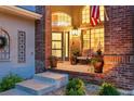 Charming front porch with brick accents, decorated with plants, seating, and an American flag at 505 Orchard Dr, Louisville, CO 80027
