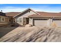 An inviting home showcasing a beige exterior, an attached garage, and an expansive driveway at 7679 S Biloxi Way, Aurora, CO 80016