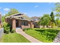 Quaint brick home with inviting curb appeal, set on a green lawn under a clear sky at 3332 N Vine St, Denver, CO 80205