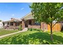 Brick home with manicured lawn, sidewalk, and mature tree providing shade in the front yard at 3332 N Vine St, Denver, CO 80205